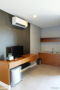 a room with a desk with a television and a air conditioner at C Cha-Am Hotel in Cha Am