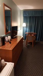 Habitación de hotel con escritorio, espejo y mesa. en Cascades Lodge en Killington