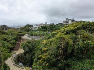 a view of a hill with trees and buildings at BigTree JUDOハウス in Urazoe