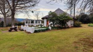 a white house with a picnic table in a yard at The Edge Mountain Retreat in Hogsback