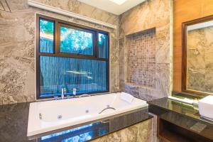 ein Bad mit einer großen Badewanne und einem Fenster in der Unterkunft Poonsiri Resort Aonang-SHA Extra Plus in Ao Nang Beach
