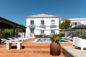 a hotel with a pool and chairs and umbrellas at Quinta do Pedro in Luz de Tavira
