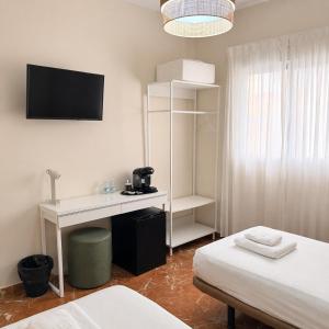 a room with a desk and a bed and a tv at La Vega Rooms in Huelva