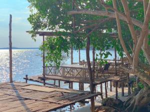 a wooden pier with tables and chairs on the water at Baankonhualamkohlibong in Ko Libong Island