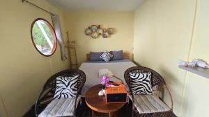 a room with two chairs and a table with a bed at Baankonhualamkohlibong in Ko Libong Island
