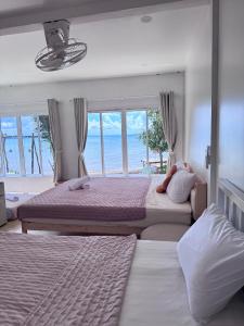 two beds in a bedroom with a view of the ocean at Baankonhualamkohlibong in Ko Libong Island