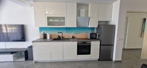 a kitchen with white cabinets and a stainless steel refrigerator at Blue Pearl Seafront in Preko