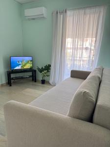 a living room with a couch and a flat screen tv at Sun Beach Apartment in Anavyssos