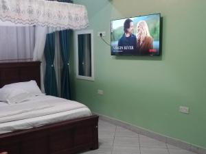 a bedroom with a bed and a tv on the wall at BRACCK Suites in Nakwero