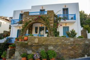 a house with a stone wall and flowers at Andros Guesthouses in Andros