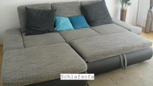 a gray couch with two pillows on it at Ferienwohnung Notos- Eislingen in Eislingen