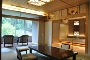 a living room with a table and chairs and a bed at Arima Onsen Gekkoen Korokan in Kobe