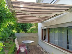 a patio with a table and chairs under awning at Ferienwohnung Notos- Eislingen in Eislingen