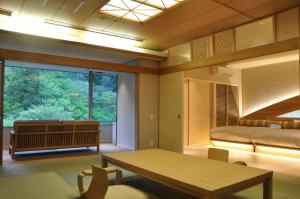 a room with a table and a bed and a window at Arima Onsen Gekkoen Korokan in Kobe