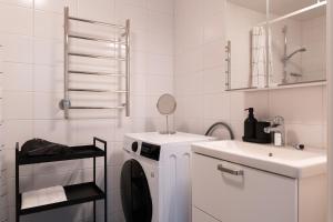 a white bathroom with a washing machine and a sink at Guestly Homes - Central Premium Suite 1BR in Västerås