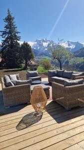 a patio with couches and a table on a wooden deck at Chalet de Manigod in Manigod