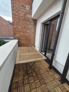 a balcony with a wooden floor next to a brick wall at Flexi flat Gosselies Providence 12 in Charleroi