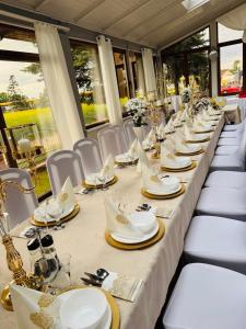 a long table with white plates and napkins on it at Hotel Jan in Zgorzelec