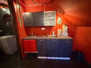 a small kitchen with a sink and orange walls at Intimissima apartman in Odorheiu Secuiesc