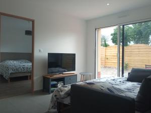 a bedroom with a bed and a tv and a desk at Gîte du Bois de Drancourt in Drancourt