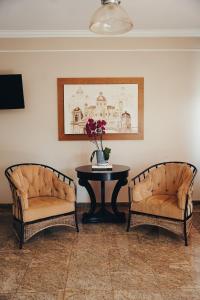 two chairs and a table with a vase of flowers at Candeias Hotel in Batatais