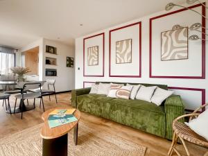a living room with a green couch and a table at Escale Doullennaise - Appartement neuf avec terrasse in Doullens