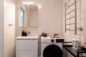 a white bathroom with a washing machine and a sink at Guestly Homes - Central Smart Studio in Västerås