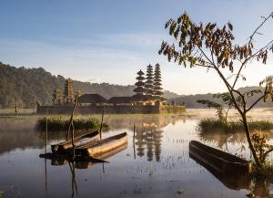 a boat in the water with a temple in the background at Wana Wooden House in Munduk