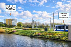a train is stopped next to a river at Hotel Fogo Amsterdam in Amsterdam