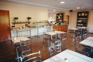 a restaurant with tables and chairs and a counter at Candeias Hotel in Batatais