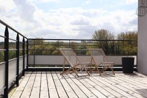 two chairs sitting on the deck of a balcony at Escale Doullennaise - Appartement neuf avec terrasse in Doullens