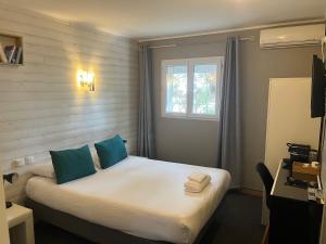 a room with a bed with blue pillows and a window at Hôtel Lapeyronie in Montpellier