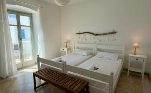 a bedroom with a white bed and a bench at Piperi On The Rocks in Naousa +28 photos