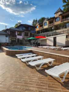a row of chaise lounges next to a swimming pool at Семеен хотел Струма in Boboshevo