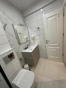 a white bathroom with a toilet and a sink at Ajsel Luxury Rooms in Sarandë +34 photos