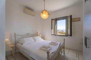 a bedroom with a white bed and a window at Infinity Blue - Villa A in Aspro Chorio Paros +17 photos