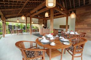 una sala da pranzo con tavoli e sedie in legno di Sativa Villas Ubud with Private Pool ad Ubud