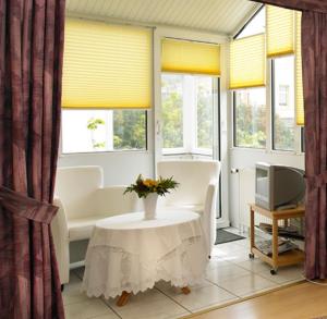 a living room with a table and chairs and windows at Hotel Sylvia in Norderney