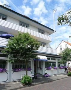 a white building with a tree in front of it at Hotel Sylvia in Norderney