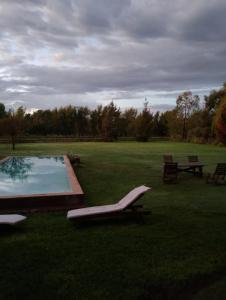 a swimming pool in a field with a picnic table and benches at Los Patios Haras El Malacate in A. de la Cruz