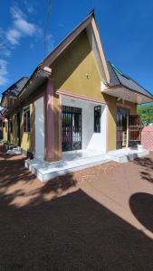 a small yellow and white building with a gate at Mamayi Homestay in Mto wa Mbu