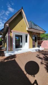 a small yellow and white house with a driveway at Mamayi Homestay in Mto wa Mbu