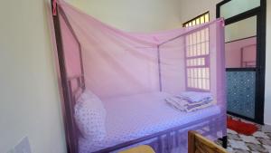 a bedroom with a pink canopy bed with a window at Mamayi Homestay in Mto wa Mbu