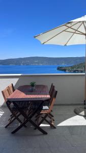 a table and chairs on a balcony with an umbrella at Villa Nika & Eva Valun in Cres
