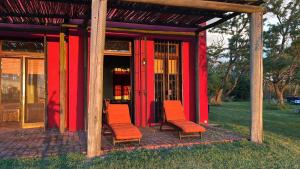 a red building with two chairs in front of it at La Negrita Casa de Campo in Azcuénaga