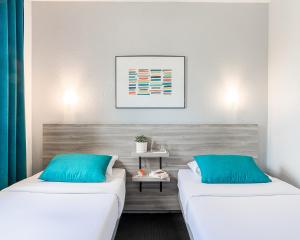two beds in a room with blue pillows at Hôtel Lapeyronie in Montpellier