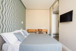 a bedroom with a white bed and a flat screen tv at Weaver Suites By Dimorra in Naples
