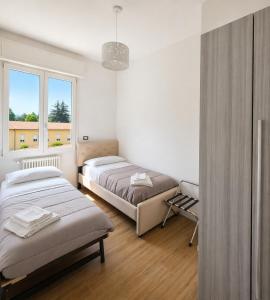 a bedroom with two beds and a window at Central Chic Apartment in Imola