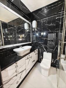 a black and white bathroom with a sink and a toilet at Rudra BNBF in Gandhidham
