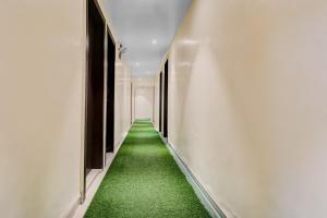 an aisle with green carpet in a hallway at Hotel O Parinda Lodging in Chinchwad